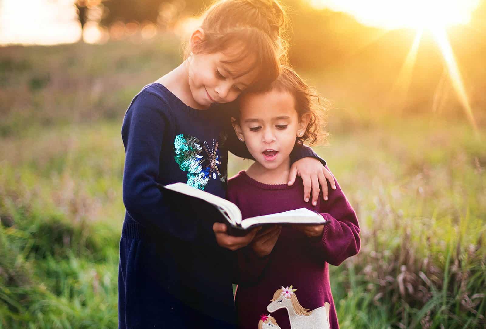 dos niñas leyendo un libro en medio de la naturaleza